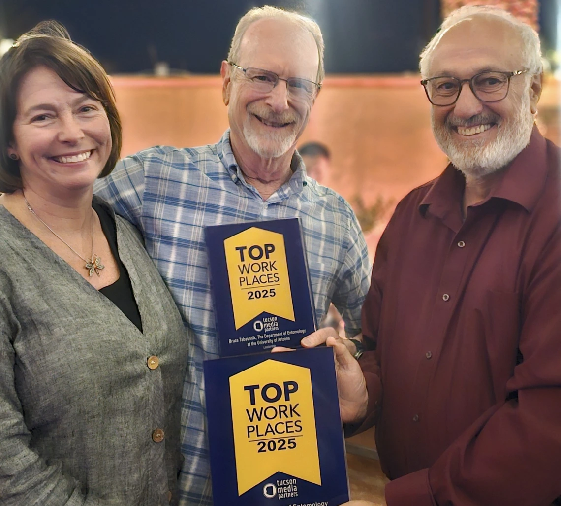 Faculty and department head hold up the plaque celebrating the department being a named a Top Workplace
